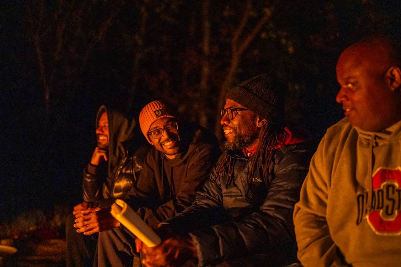 Men laughing together by the fire at night