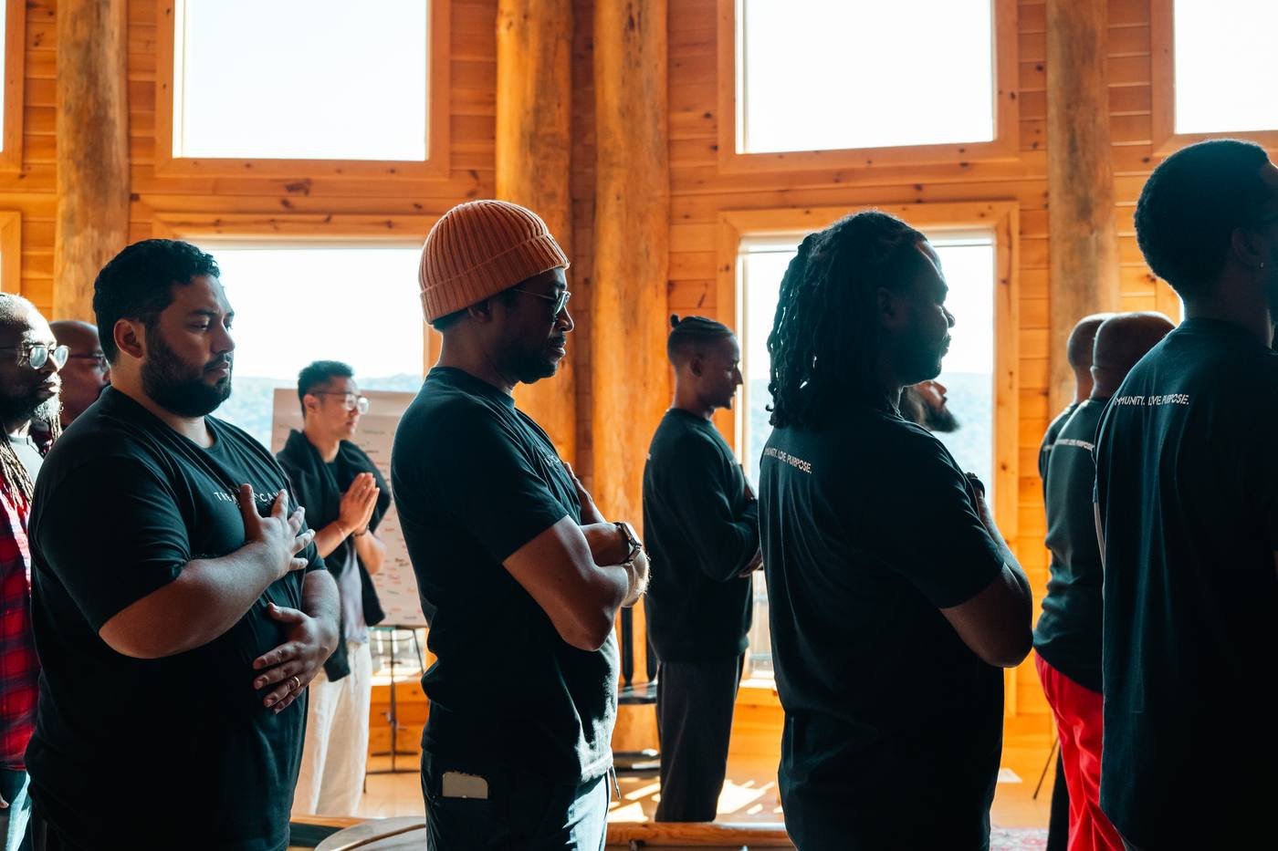 Men standing with hands on their hearts in a sunlit cabin