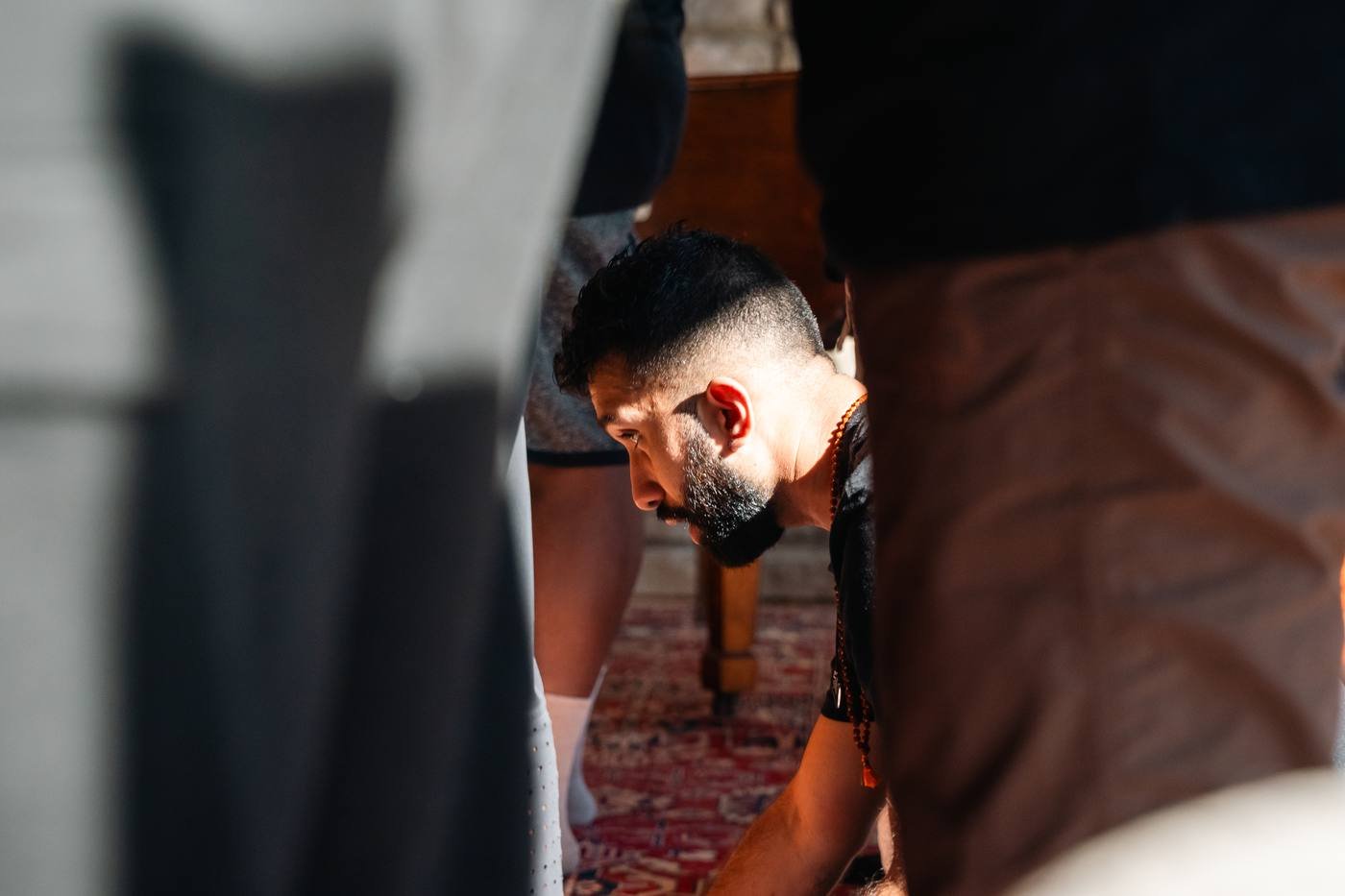 A man kneeling in focus, framed between the legs of the men around him