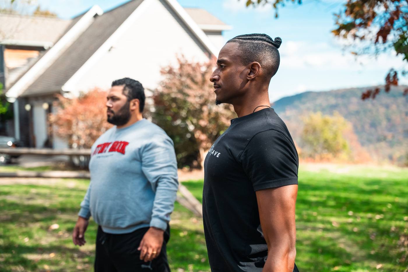 Two men standing outside with mountains behind them