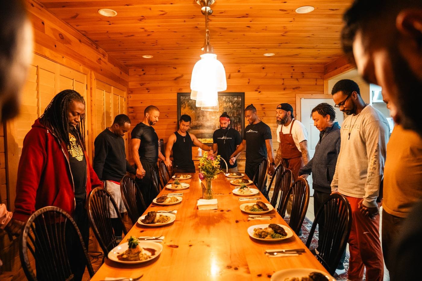 Men standing around a long table sharing a meal