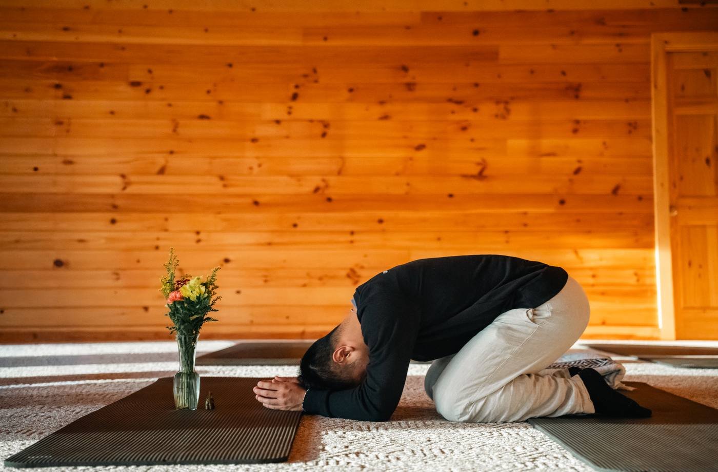 A man resting in child’s pose on a mat